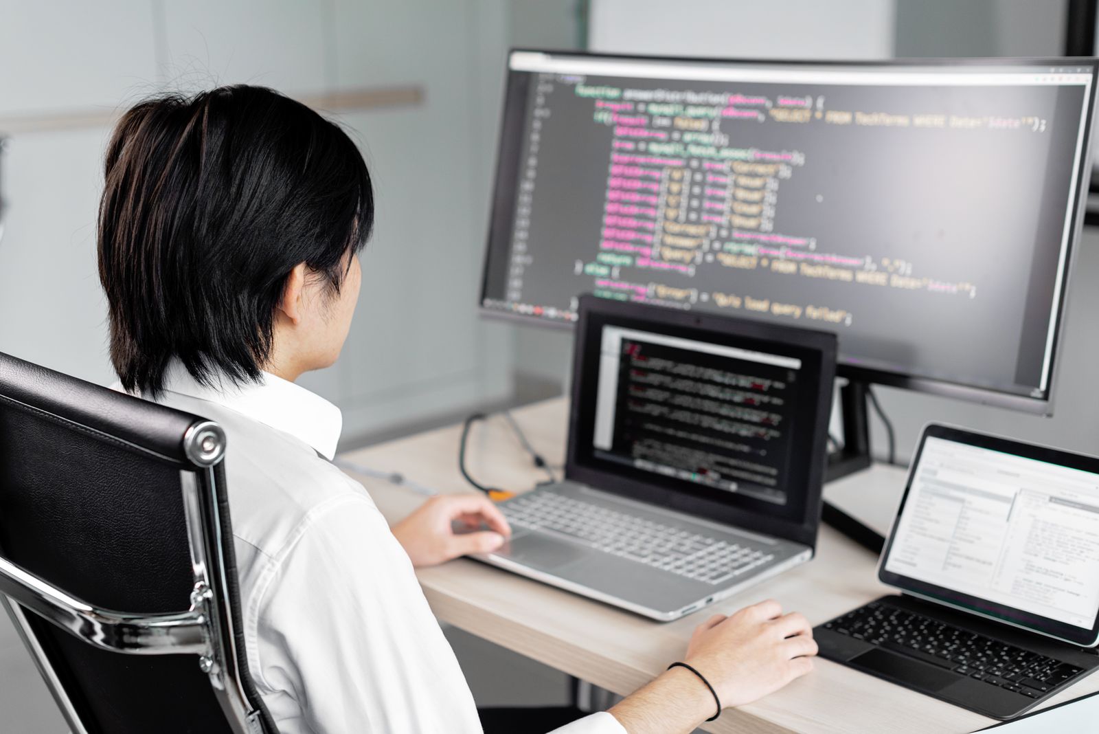 Softwareentwickler arbeitet mit mehreren Bildschirmen an einem Arbeitsplatz