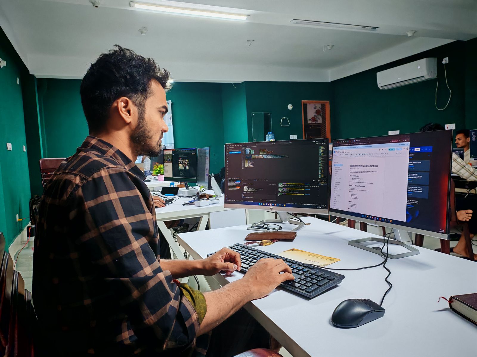 Softwareentwickler arbeitet an einem Arbeitsplatz mit zwei Monitoren